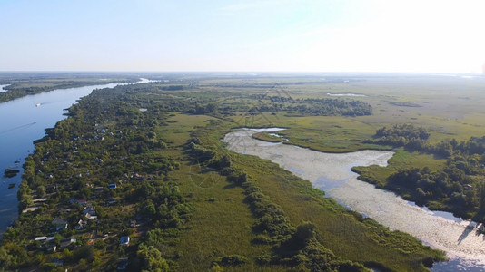 绿色当地的无人驾驶飞机越由当地村庄包围的摇晃蓝色河流上空周围有各种建筑物和湿地及沼泽生境并有共同里德航空视野的后座草图片