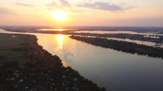 银行农场无人驾驶飞机越由当地村庄包围的摇晃河流周围有各种建筑物和湿地及沼泽生境日落顶风景是共同Reed空中观察的后座户外图片