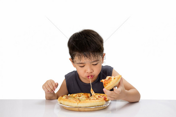 亚洲男孩很高兴吃比萨饼热奶酪融化在木板上拉伸把白的孤立新鲜番茄青年图片