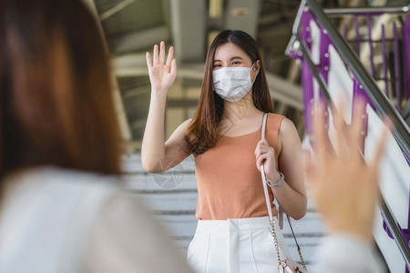身戴外科面具的亚洲年轻女乘客在Covid19疫情爆发社会动荡与新常态概念等大城市旅行时用手挥向地铁列车朋友打招呼日本人健康韩国图片