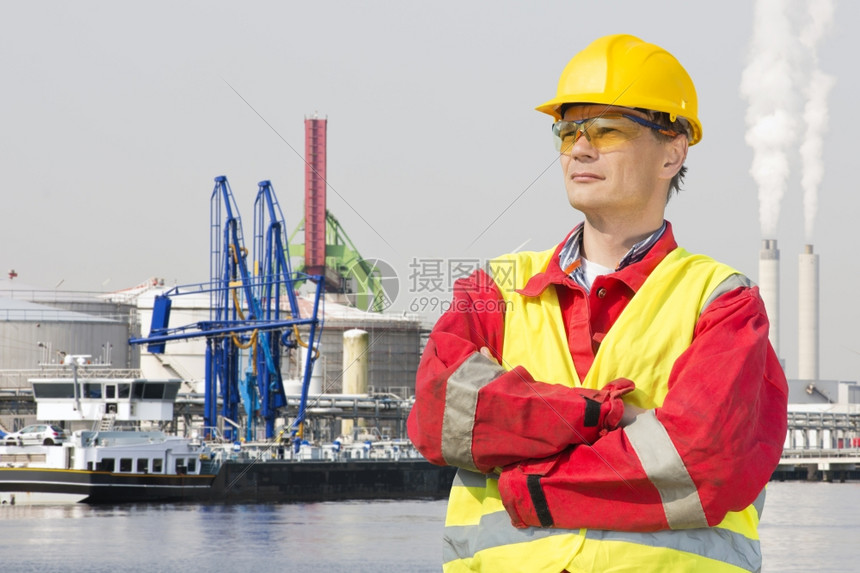 工程师穿着安全装备站在他的手臂交叉和自信骄傲的表情在工业港口面前朝着他的脸风镜工人阳光图片