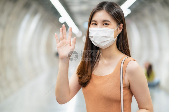 韩国人女士主教年轻的亚洲女乘客身戴外科面罩看着照相机与朋友在地铁交汇处打招呼或问候在Covid19疫情爆发的大城市旅行时这是新的图片