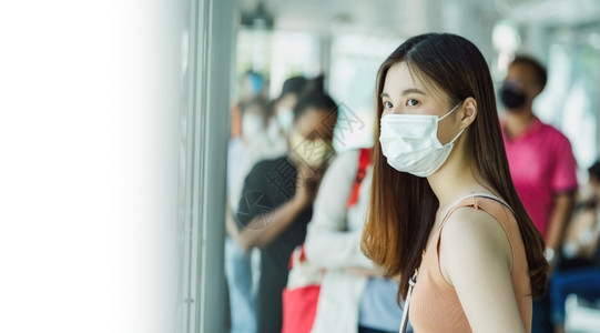 在科维德爆发感染和大流行病概念的都市旅行时身着外阴面罩和在车站与加冕者一起等待公共汽车的亚洲女青年乘客曼谷脸网络图片