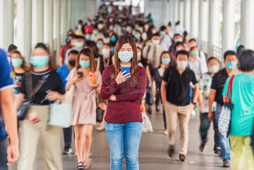 脸亚洲女在曼谷交通高峰时段工作日使用手机包括身戴外科面罩的模糊且无法辨认的商人以防止冠状爆发在曼谷交通中超时工作严肃的办公室图片