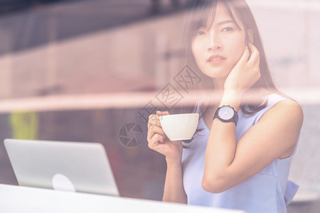 沟通亚洲妇女利用智能手机在现代咖啡店线购物持有和喝咖啡技术钱包和网上支付概念信用卡模型等亚洲妇女使用智能移动电话在现代咖啡店进行图片