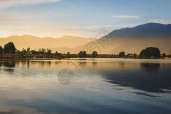 乡村男人国民美丽的风景在达尔湖平静的水面上多彩夕阳天空和传统船Shikara影子斯利那加查谟克什米尔北部中亚图片