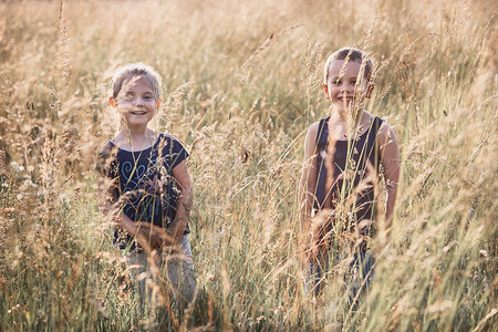 快乐笑的小孩子们在乡下高草地上玩耍坎迪德人真实的时刻情况夏令正公园图片