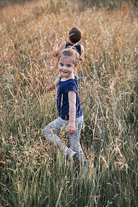 欢乐的男趣快笑的小孩子们在乡下高草地上玩耍坎迪德人真实的时刻情况图片