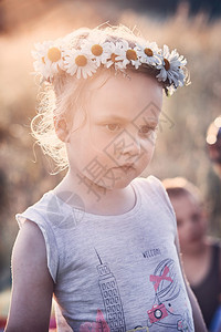 小姑娘头上戴着野花真正的瞬间实情境身披鲜花的宝网一种父母快乐的图片