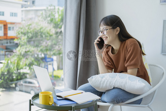 快乐的年轻女孩在家电话上聊天打应答电话与朋友通过手机聊天愉快地交谈和朋友通话八卦随意的女商人图片