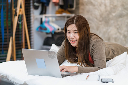 自己移动的无线亚洲商业妇女使用技术笔记本电脑在家室内卧工作自由与企业家创和者企主生活方式职业社会距离和自我责任等亚洲商业妇女图片