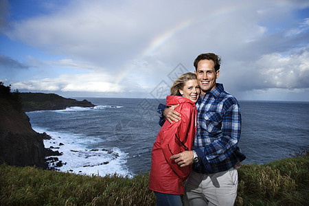 笑得开心的情侣海滩两个人雨衣微笑观众假期旅行海岸拥抱照片图片