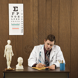 医生在书桌写作专注医疗职业照片中年保健男性器材卫生木头背景图片