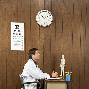 医生在书桌器材办公室中年木头保健卫生男子正方形视力表工作图片