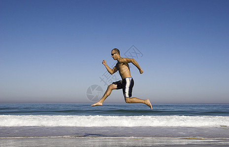 男人在海滩上奔跑和跳跃体操成人运动乐趣活力天空蓝色青少年空气自由图片