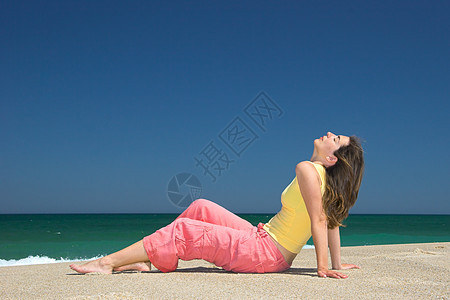 美丽的年轻女孩在沙滩上放松太阳运动姿势天空喜悦冒充时间女性活力乐趣图片