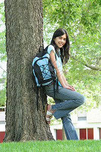 年轻的少女站在背着背包的树上混血精力中学学生女孩孩子青少年晴天图片