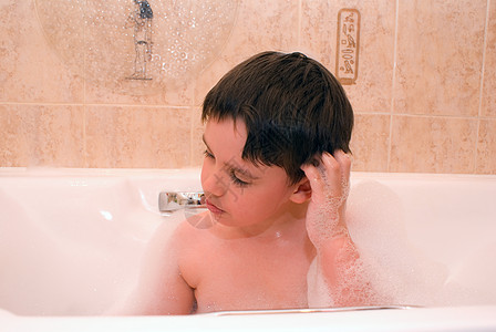 躺在地上男孩一个男孩的脸脸 特写在浴缸 用白泡沫背景