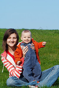 幸福的母亲 儿子坐在绿草地上童年喜悦亲热家庭快乐蓝色女士衣服男生公园图片