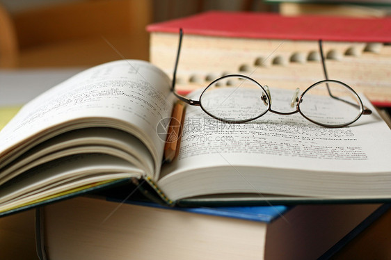带眼镜和铅笔的放在桌上的教科书图片