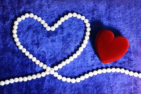 红色的红心和蓝色天鹅绒上的珍珠花束奢华项链细绳宝石白色珠宝图片