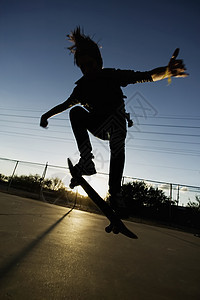 日落日落时的青少年滑板机图片