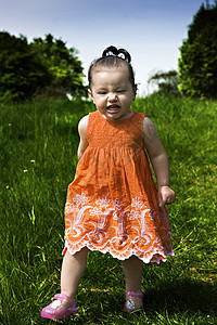 女婴在公园里跑过头发裙子女孩孩子橙子女性孩子们童年儿童天空图片