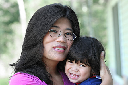 亚洲母亲亲爱地抱着儿子混血儿微笑妈妈女士男生父母精力拥抱儿童眼镜图片