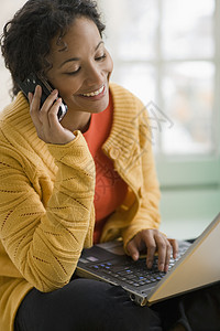 手机和笔记本电脑上的漂亮黑人妇女讲话技术微笑黑色女孩女性成人通讯沟通呼唤图片