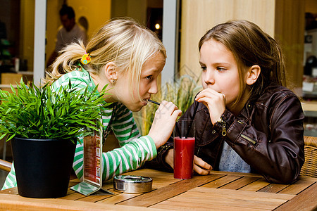 两个女孩喝果汁衬衫桌子植物街道姐妹女孩们童年牛仔裤二人购物中心图片