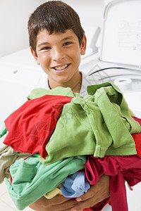 年轻男孩拥有洗衣池的粪便家庭生活打扫洗衣房洗衣机青春期休闲家务微笑帮助洗衣店图片