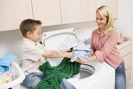 母亲和儿子洗衣服洗衣机休闲小学微笑洗衣房衣篮女士家务两个人年龄图片