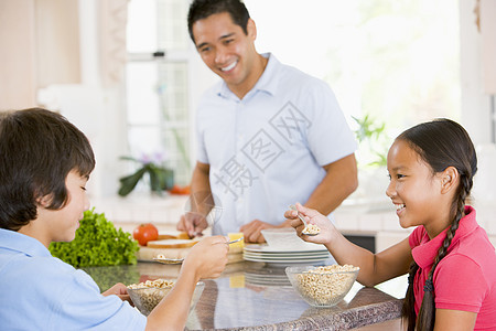 儿童在爸爸准备食物时吃早餐孩子姐姐孩子们烹饪女儿兄弟时间厨房儿子兄弟姐妹图片