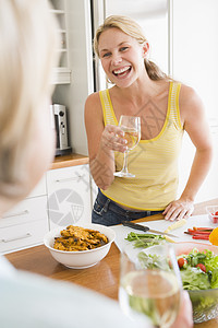 女人在准备饭菜时和朋友聊天 吃饭时间中年家长母亲蔬菜酒精烹饪团结晚餐厨房用餐图片