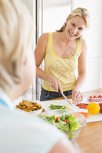 妈妈的饭菜女人在准备饭菜时和朋友聊天 吃饭时间微笑团结肩视图用餐母亲晚餐食物蔬菜两个人厨房背景
