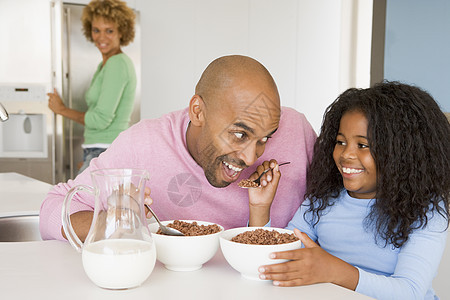 父亲和女儿一起坐着 就像他们与她一起吃早餐一样男人刀具中年厨房母亲享受孩子桌子微笑食物图片