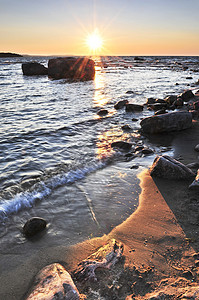 日落在水上海洋湖泊海滩地平线环境鹅卵石天空反思海岸线石头图片