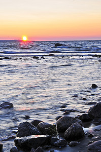 日落在水上石头风景岩石海洋天空湖岸海滩反射海岸线公园图片