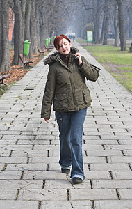在秋天公园散步公园女性季节行人胡同牛仔裤女性化夹克学生红发图片