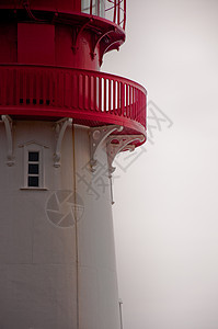 红色和白色灯塔窗户航海安全海岸天空地标建筑房子灰色导航背景图片
