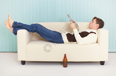 人们舒适地躺在沙发上看杂志图片