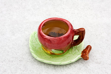 雪地背景上一杯茶飞碟茶托叶子黑色图片