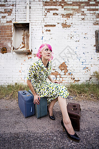 粉色头发和小手提箱的女人时尚褶皱钱包电源线姿势手提箱化妆品女士裙子胡同图片
