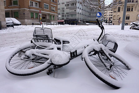 下雪覆盖的坠落自行车城市车轮座位气候街道天气建筑物运输白色踏板图片