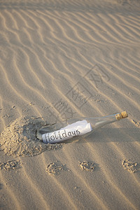 在沙中装瓶子场景脆弱性日落海浪热带假期孤独玻璃黄色气候图片