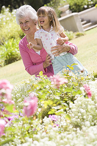 外祖母和外孙孙女在花园的户外露天微笑老年女孩院子植物亲密感孙辈祖母蹲伏孙子孩子图片
