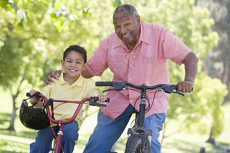 外祖父和孙子在户外骑自行车时微笑着笑活动家庭男人男性儿子祖父安全帽祖父母男生骑术图片