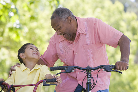 外祖父和孙子在户外骑自行车时微笑着笑农村男生家庭老年祖父安全帽骑术头盔孩子公园图片