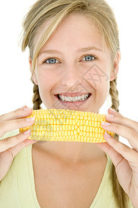 年轻女孩拿着玉米在鳕鱼上 微笑着笑图片
