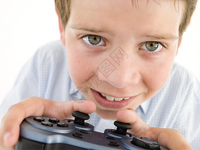 年轻男孩使用视频游戏控制器微笑男生娱乐影棚孩子相机头肩手柄情感专注乐趣图片